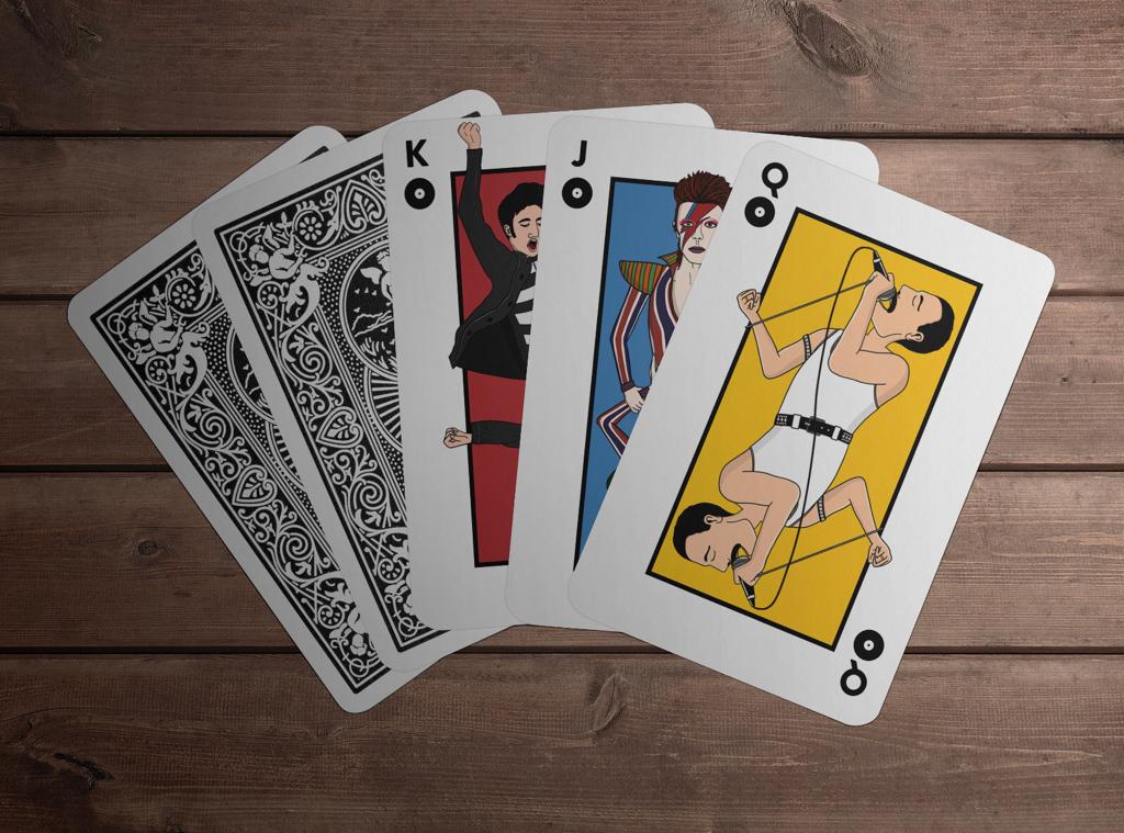 Playing cards layed on a table with illustrations of Elvis Presley, David Bowie, and Freddie Mercury as head figures.