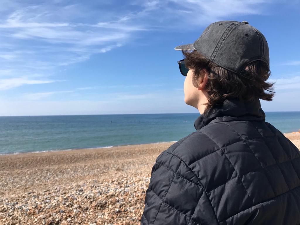 John Bellingall sitting in front of the sea shore.